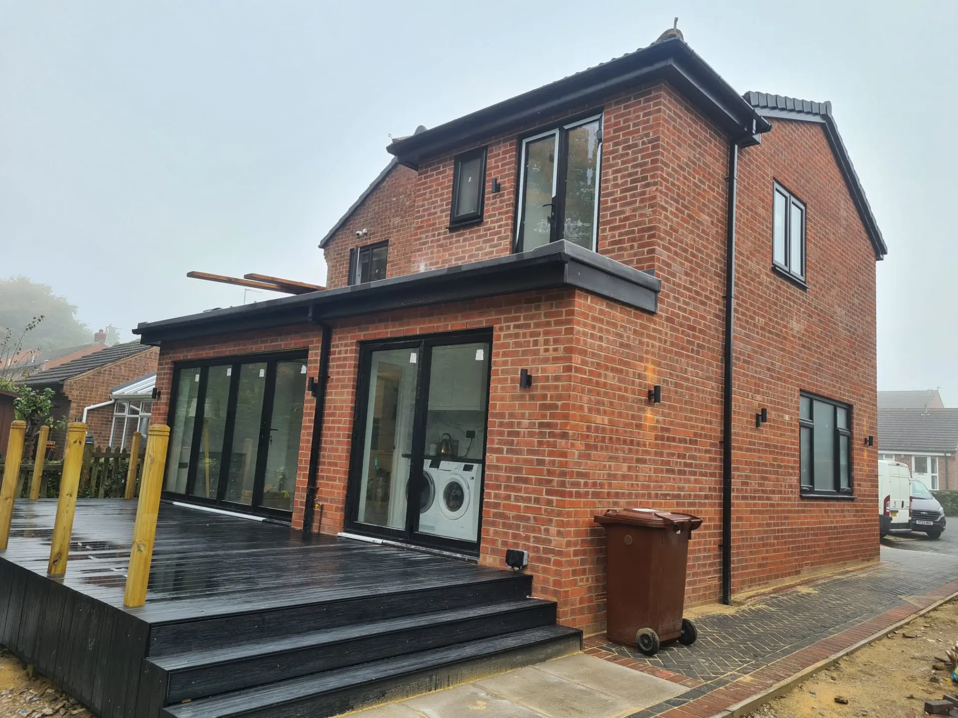 Two-storey brick extension in Leeds with black bi-fold doors and composite decking