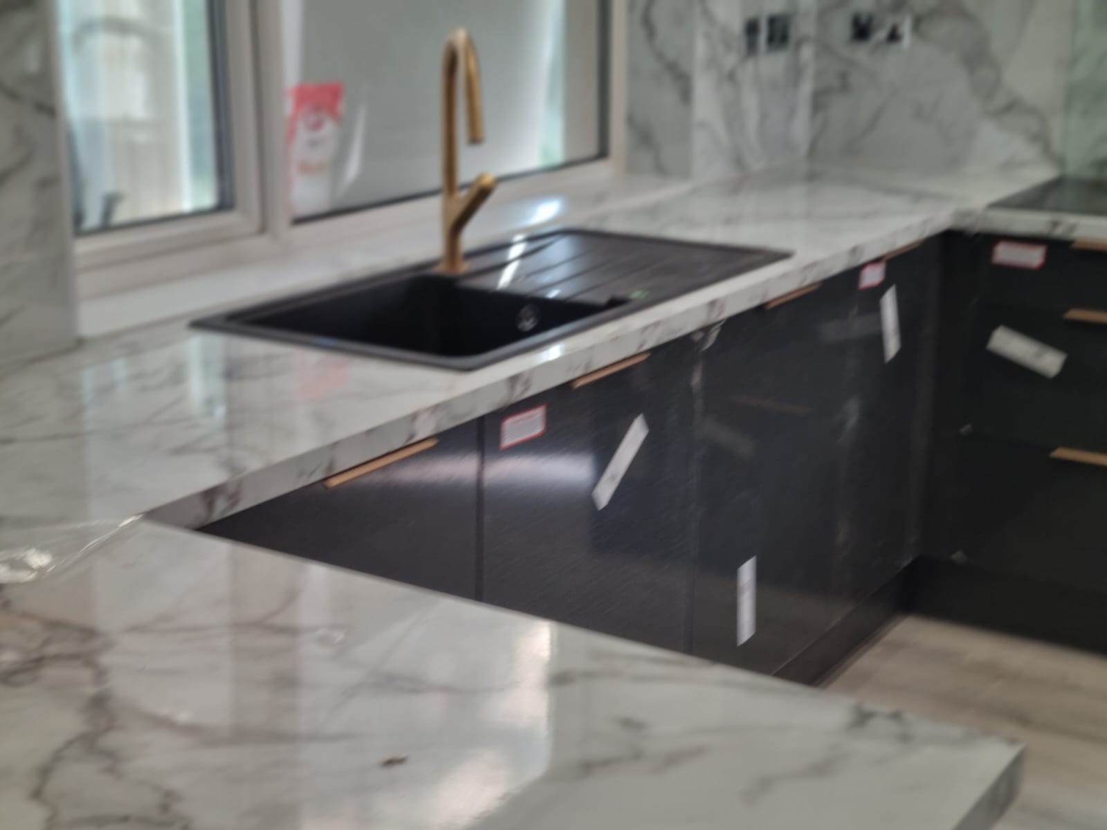Close-up of black kitchen sink and gold tap on marble worktop, Leeds kitchen