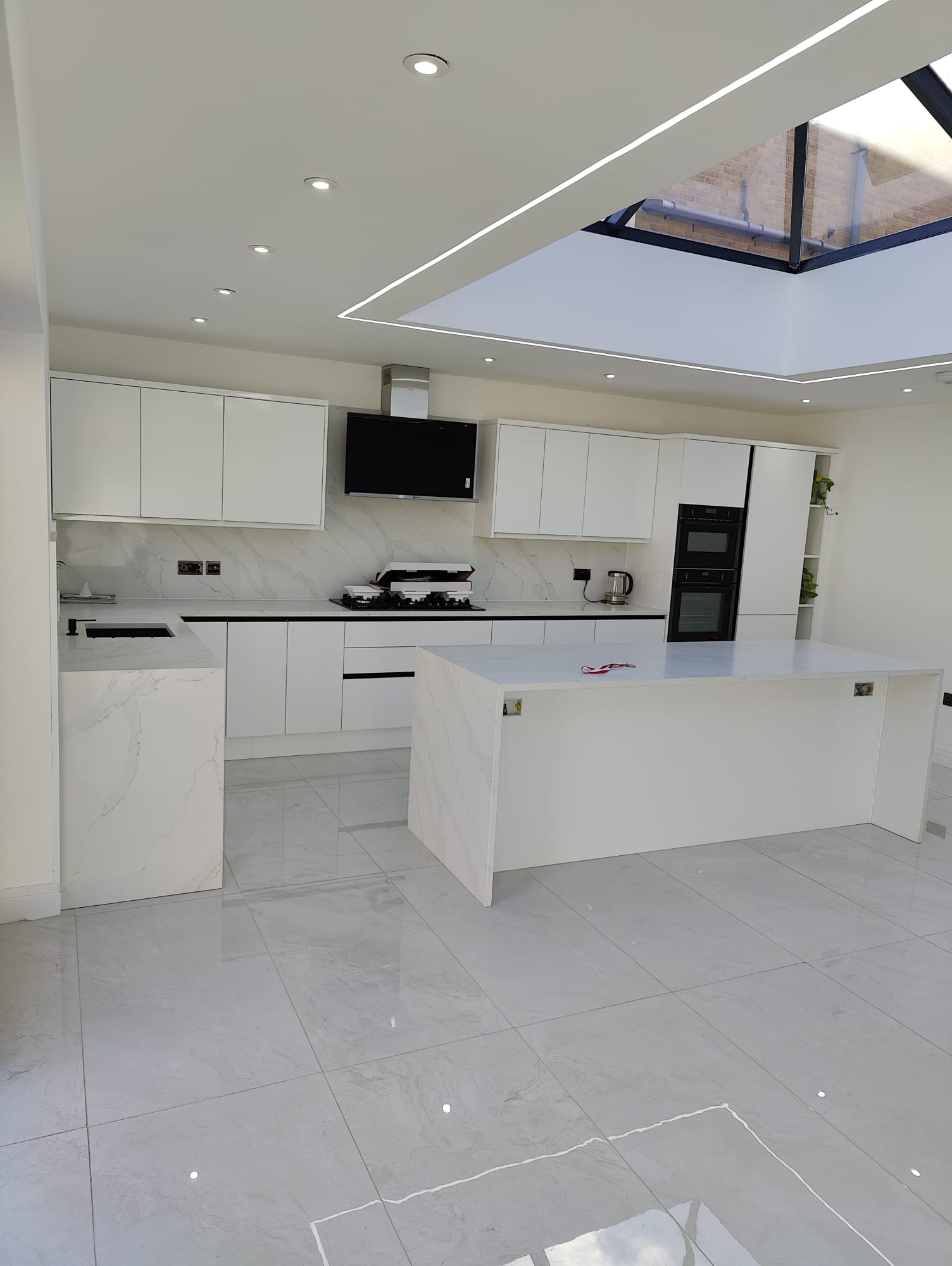 Completed rear house extension in Leeds with glazed roof lantern, white handleless kitchen and marble island